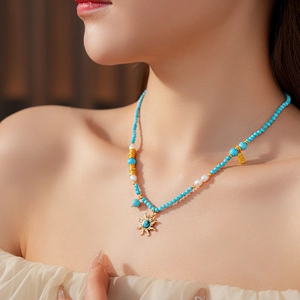 Détail du collier de perles avec perle d'eau douce, pendentif soleil et breloque dorée
