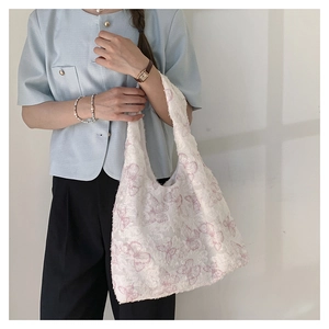 Detailed close-up of white tote bag with pink butterfly embroidery on a textured fabric
