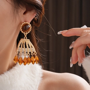 Detail of vintage gold fan-shaped earring with tiger eye stone and amber beads