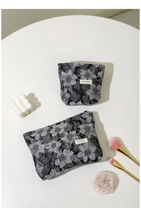 Détail des trousses à maquillage en jacquard français avec pinceaux dorés.