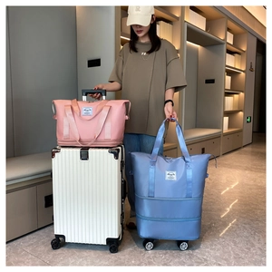 Blue expandable travel bag with wheels and pink duffel bag shown on a white suitcase