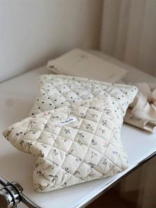 Detailed view of quilted corduroy cosmetic bags with floral prints and brand label
