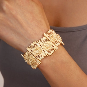 Detail of vintage gold wide bracelet featuring embossed floral patterns on wrist