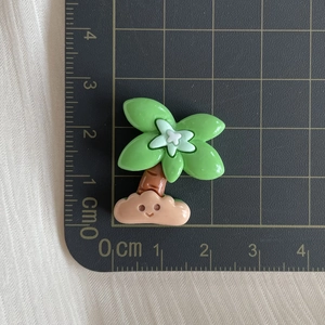 Detailed macro view of a cartoon resin tree charm with a smiley face on a grid mat