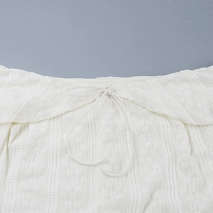 Close-up of white lace texture and drawstring detail on a backless mini dress