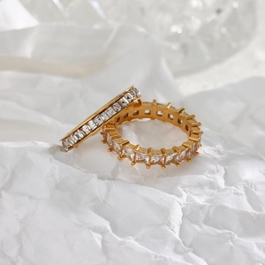 Close-up of gold and silver eternity rings with baguette-cut zircons on white paper