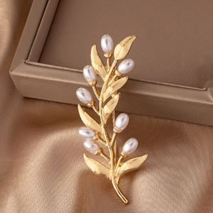Vintage golden olive leaf brooch with white pearls displayed on silk fabric background