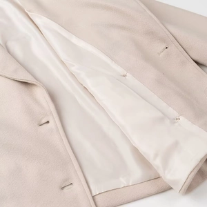 Detailed close-up of beige wool coat interior featuring smooth lining and buttonholes