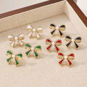 Detailed view of colorful bow-shaped earrings with pearls and rhinestones on a beige tray
