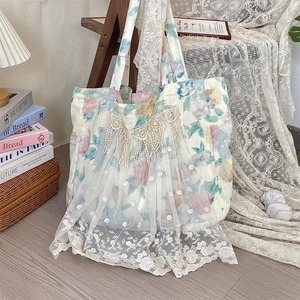 Detalle del bolso de lino floral con bordado de encaje blanco y detalles de borlas