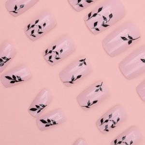 Detailed view of pink press-on nails featuring elegant black leaf floral painting designs