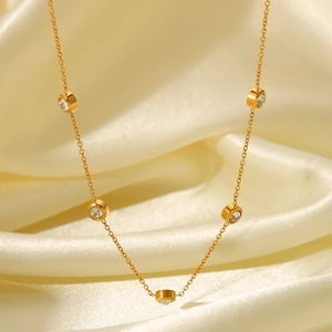Detail of round cubic zirconia on 18K gold-plated chain over elegant beige silk fabric