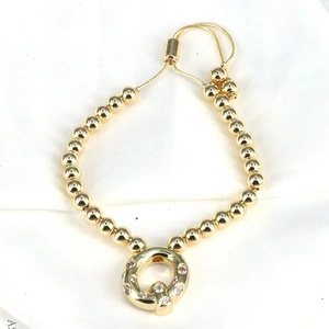 Close-up of golden beaded bracelet with zircon pendant and adjustable slider clasp