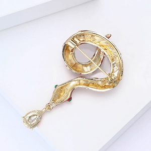 Detailed macro view of golden snake brooch with red and green enamel and inlaid gems