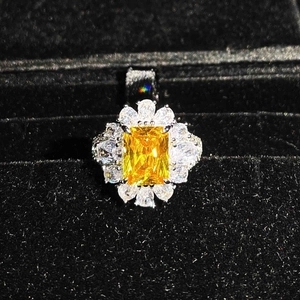 Macro shot of rectangular yellow gemstone pendant with floral diamond halo in black box
