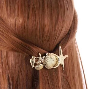 Golden starfish and seashell alloy hair clips worn on brown hair for elegant styling