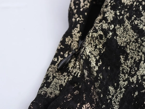 Detailed macro view of invisible zipper on black dress with gold foil texture