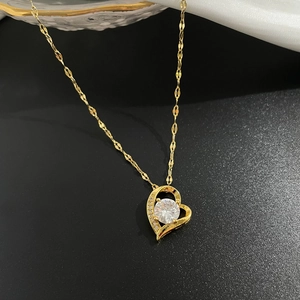 Dettaglio della collana a cuore dorata con gemma centrale su sfondo in seta bianca