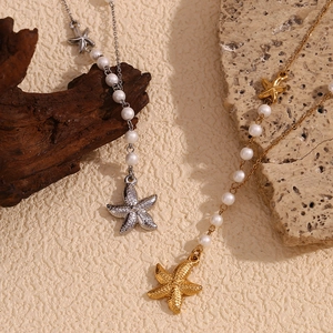 Detailed view of gold and silver starfish pendant necklaces with pearl accents on textured stone