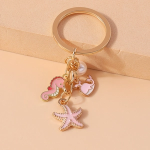 Detail of gold keychain with enamel seahorse, starfish, whale tail pendants and pearl