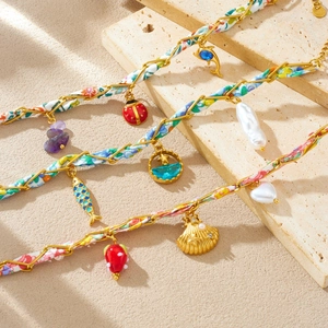 Bracelet chaîne dorée avec tissu floral et pendentifs variés tels que perles et coccinelles