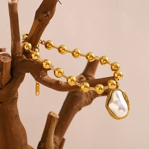 Detailed macro view of 18K gold plated bead bracelet with unique baroque pearl charm