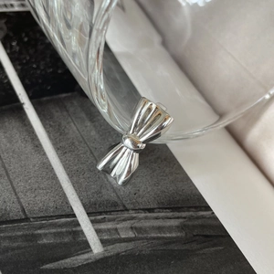 Elegant 925 sterling silver bow ring with polished vertical stripes on a glass rim