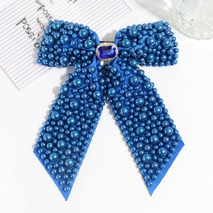 Detail view of navy blue ribbon bow hair clip with pearls and a rectangular blue gemstone