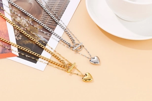 Detail of gold and silver double-layered heart necklaces with OT clasps on flat lay