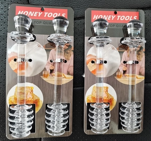 Lot de quatre cuillères à miel en verre transparent présentées dans leur emballage de vente