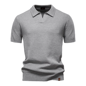 Detailed close-up of grey textured knit polo shirt fabric and a premium leather hem label
