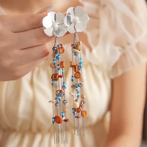 Bohemian silver flower tassel earrings with colorful beads held in hand for fashion display