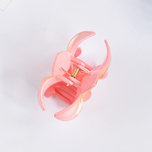Detailed macro view of a pink frangipani hair claw clip with golden metal spring