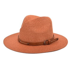 Detailed macro view of orange woven straw hat with brown leather belt and metal buckle