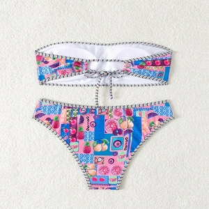 Detail eines Bandeau-Bikinisets mit tropischem Fruchtdruck und bunten geometrischen Mustern