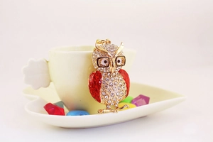 Détail du porte-clés hibou doré orné de strass brillants et d'ailes rouges