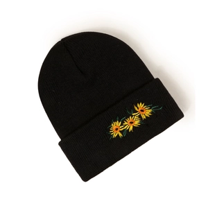 Dettaglio del berretto in maglia nera con tre ricami di girasoli gialli