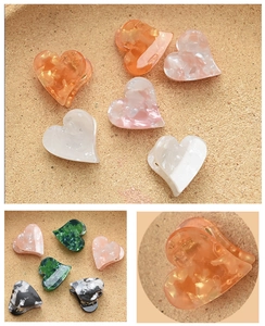 Macro detail of mini heart-shaped acetate hair clips in assorted translucent colors