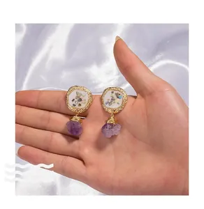 Detailed macro view of vintage gold earrings with crushed shell inlay and purple natural stone