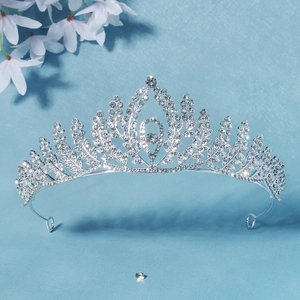 Detail of silver bridal crown with leaf-shaped crystals on a soft blue background