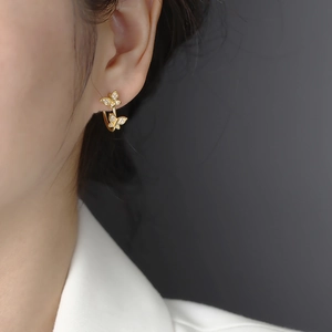 Elegante goldene Schmetterlingsohrringe mit Diamanten am Ohr eines weiblichen Models