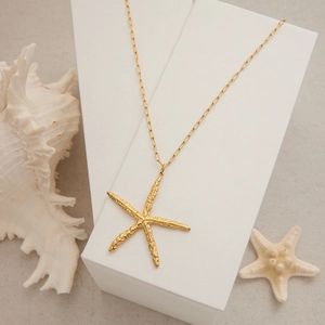 Vue détaillée du pendentif étoile de mer en or 18k sur une chaîne trombone dorée