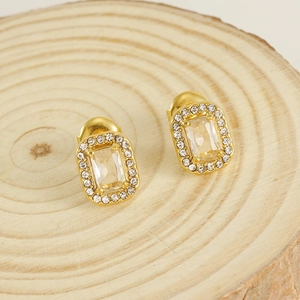 Detailed close-up of square zircon stud earrings with gold halo setting on wood