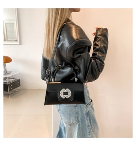 Detail of black leather crossbody bag featuring crystal buckle and ruched handle