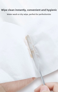 Close-up of a stainless steel spatula cleaning brown oil from a white waterproof makeup mat