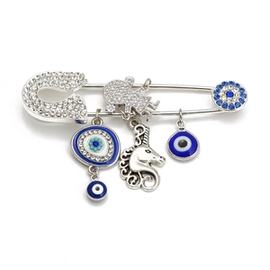 Detailed view of silver evil eye safety pin brooch with blue rhinestones and unicorn charm