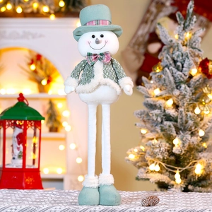 Detail of Christmas snowman doll with mint green outfit and plaid bowtie by the tree