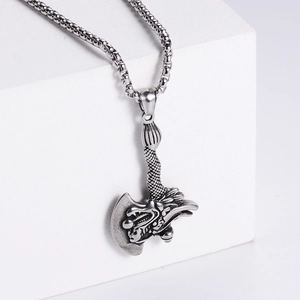 Close-up of silver dragon head axe pendant on a box chain with detailed metal engraving