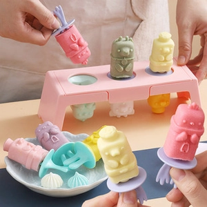 Close-up of hand holding colorful animal-shaped popsicles with silicone mold tray
