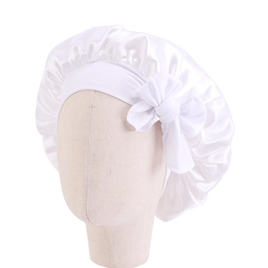Dettaglio di una cuffia da notte in raso bianco per bambini con fiocco decorativo